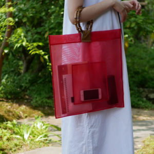 赤いカラーの竹バッグを持つ女性