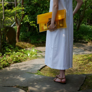 黄色の竹のクラッチバッグを持つ女性