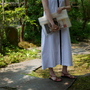 ベージュの竹のクラッチバッグを持つ女性